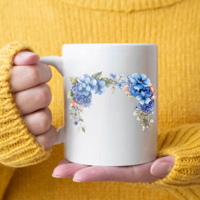Tasse à café au design floral avec fleurs blanches, bleues et feuilles vertes, adaptée au bureau à d